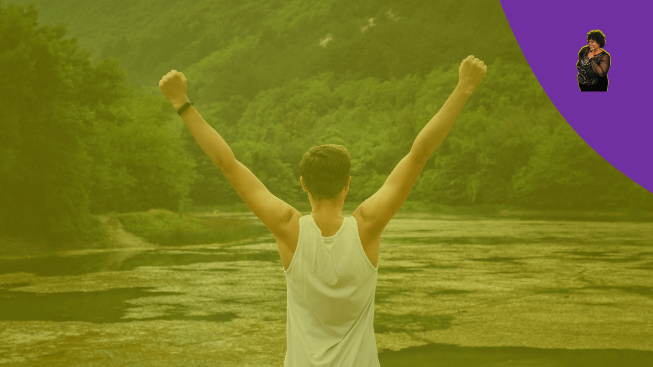 Person standing in front of water with arms raised in victory